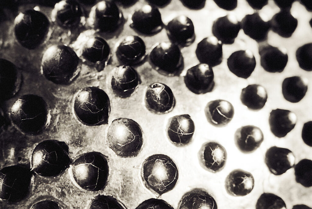 The monochrome surface of a vase rendered as cracking spheres in flame.